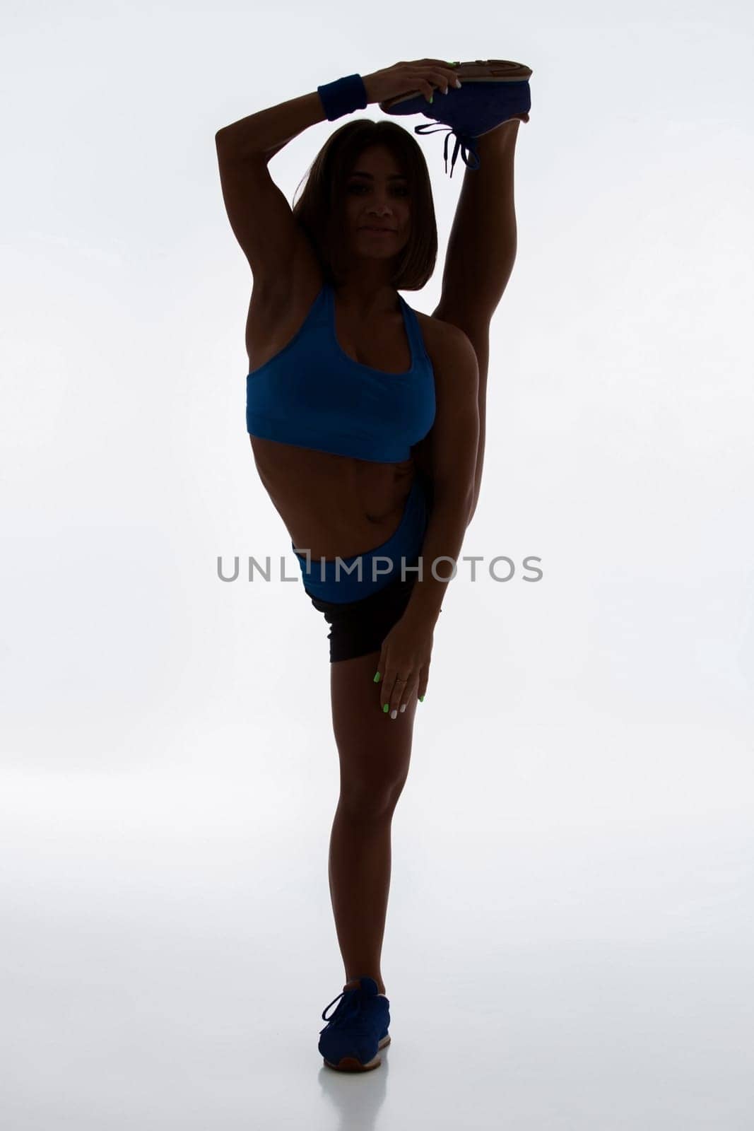 Sport and active lifestyle. Sporty flexible girl fitness woman in sportswear doing stretching exercise on light background. silhouette