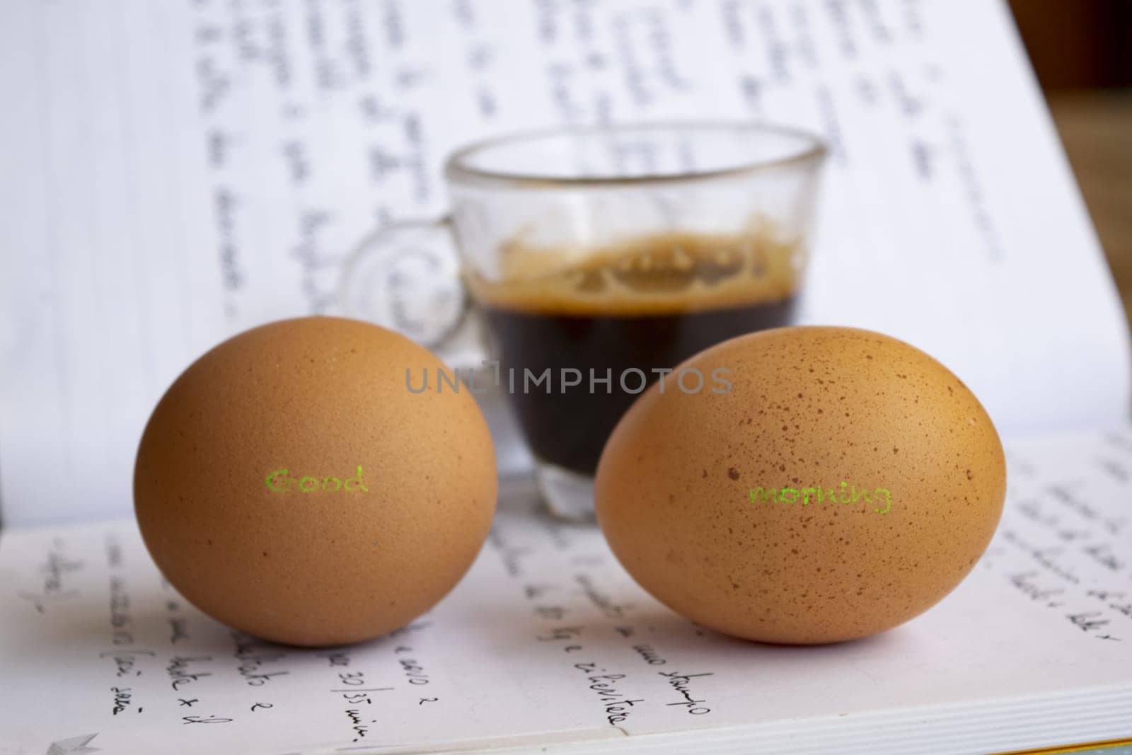 good morning message written on two eggs with a cup of coffee in the background