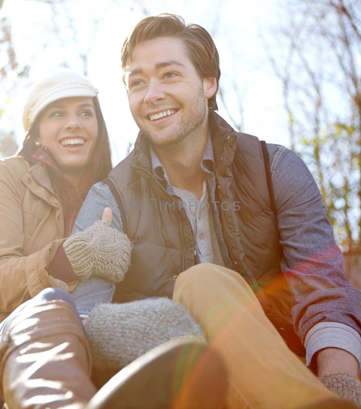 Relaxing together. A happy young couple sitting together outdoors in the woods. by YuriArcurs