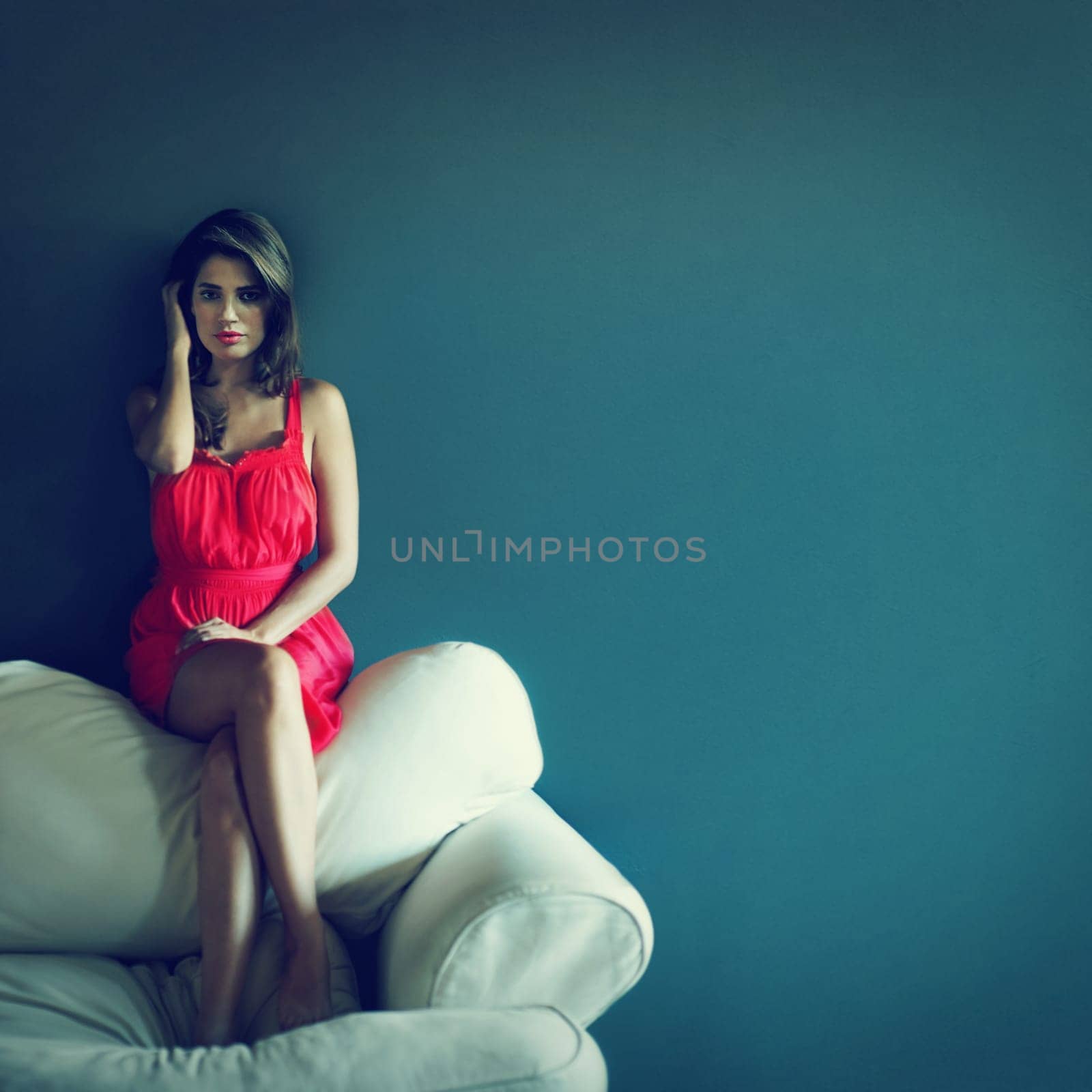 Beauty that commands your attention. A beautiful young woman with a pensive expression sitting on top of a sofa