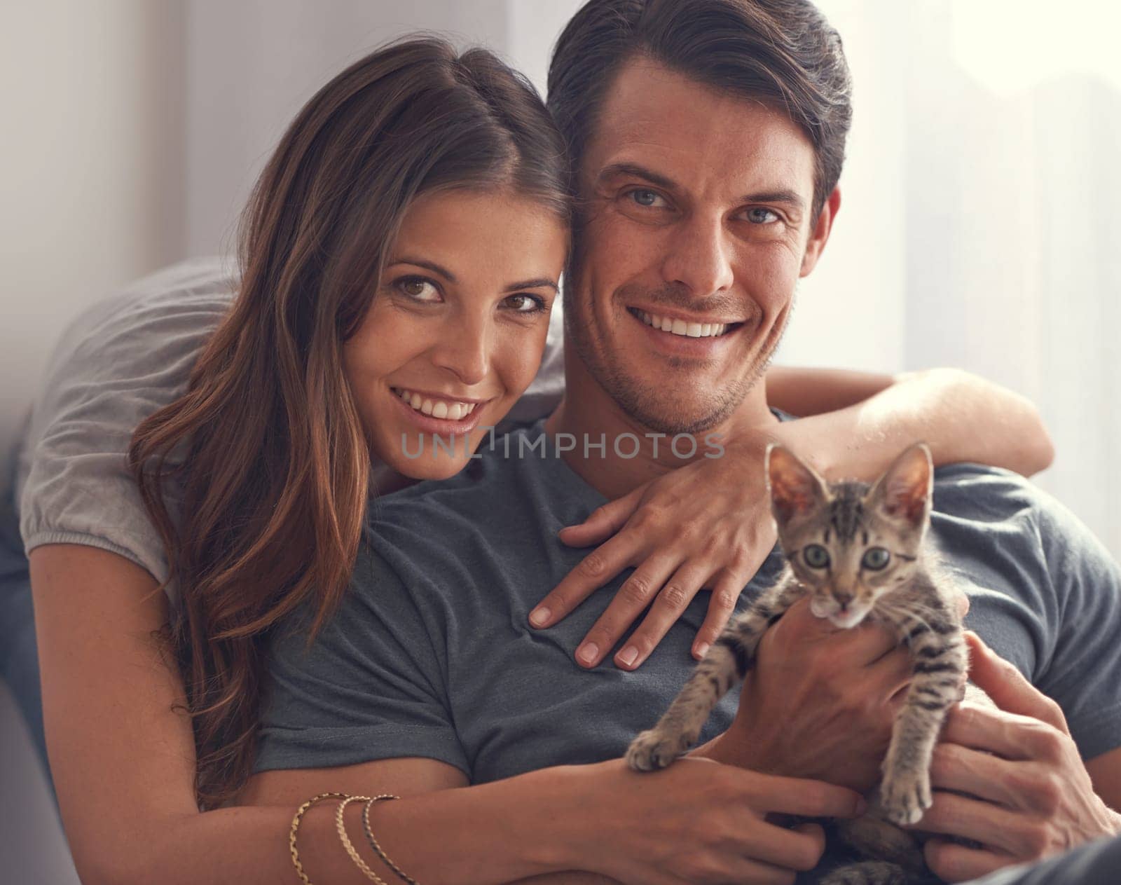 What a fluffy little angel. a loving young couple sitting with their kitten. by YuriArcurs