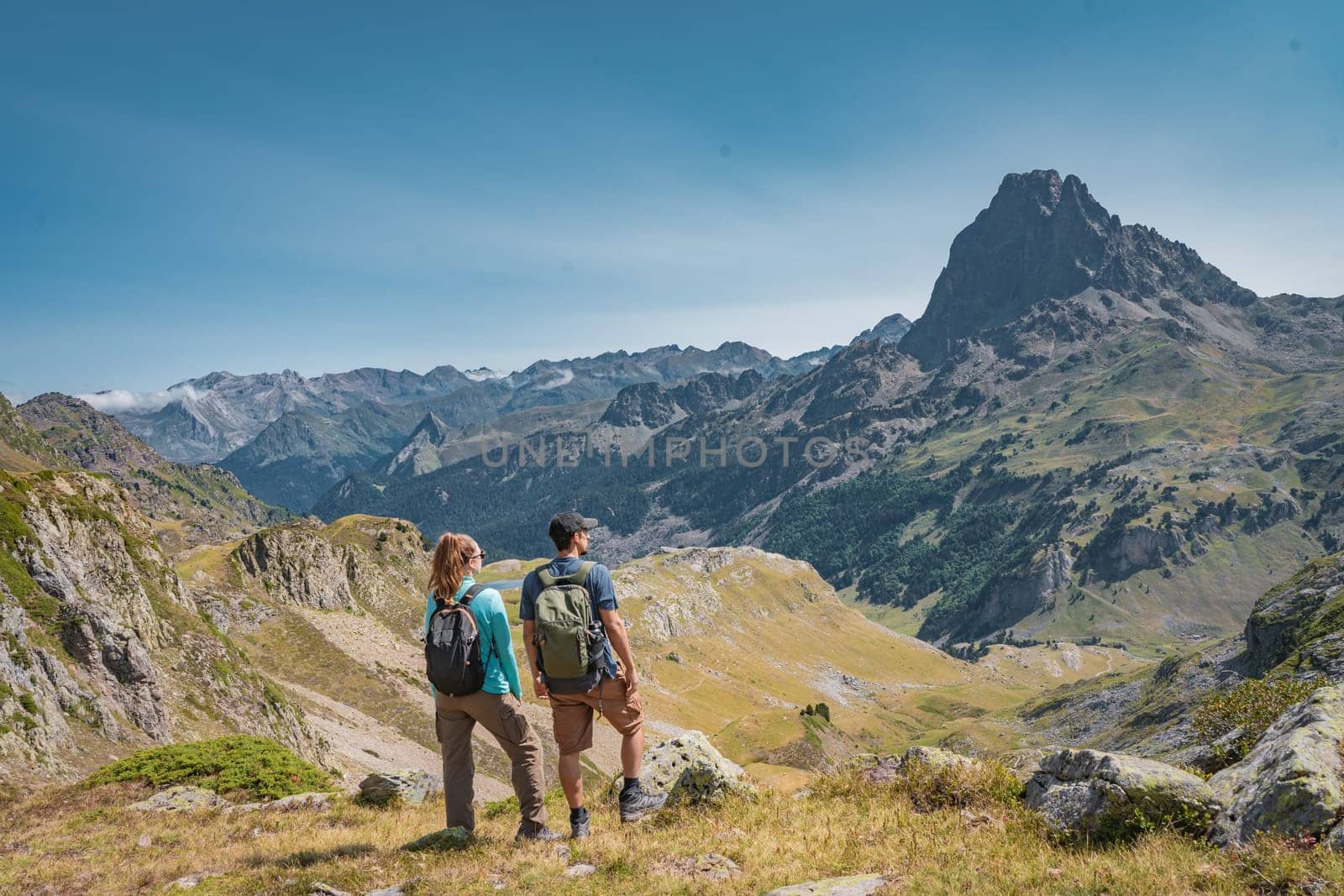 Young Attractive Couple looking the panoramic views of the amazing mountains landscape in summer. Discovery Travel Destination and Freedom Concept. High quality photo.
