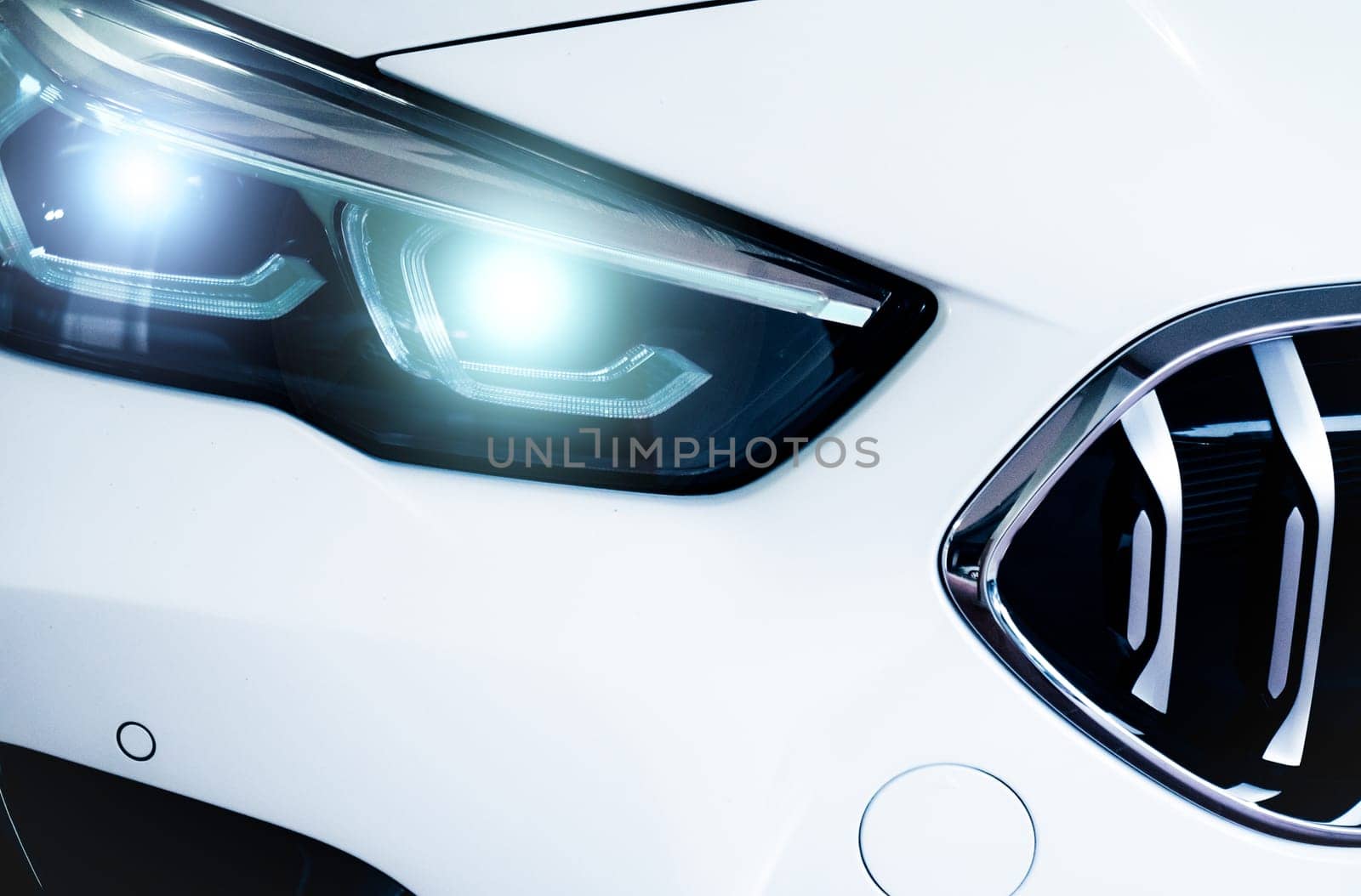 Closeup headlamp light of a white luxury car. Automotive industry concept. Electric car or hybrid vehicle concept. Automobile leasing and insurance concept. Auto leasing business. Electric vehicle. by Fahroni