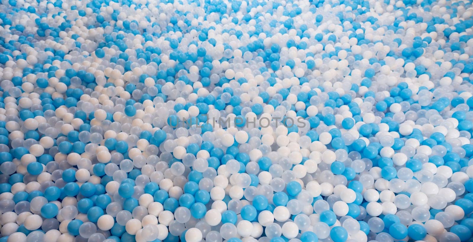 Blue and white plastic balls in ball pool at kids playground. Colorful plastic ball texture background. Many small colorful hollow plastic soft kids balls are in a ball pit. Play toy for kids.