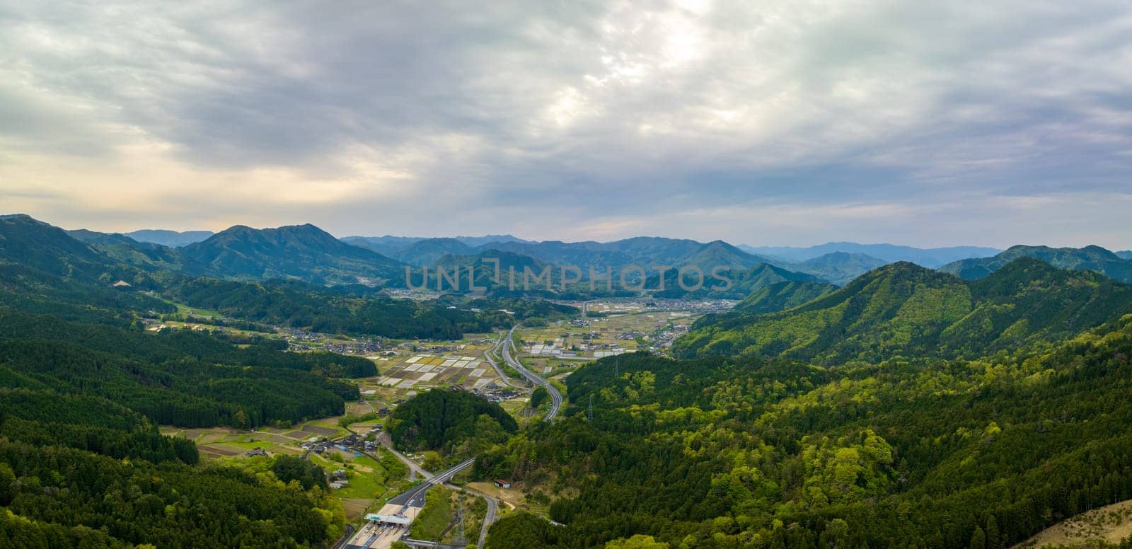 Aerial view of highway by small farming town in Japan mountain landscape. High quality photo