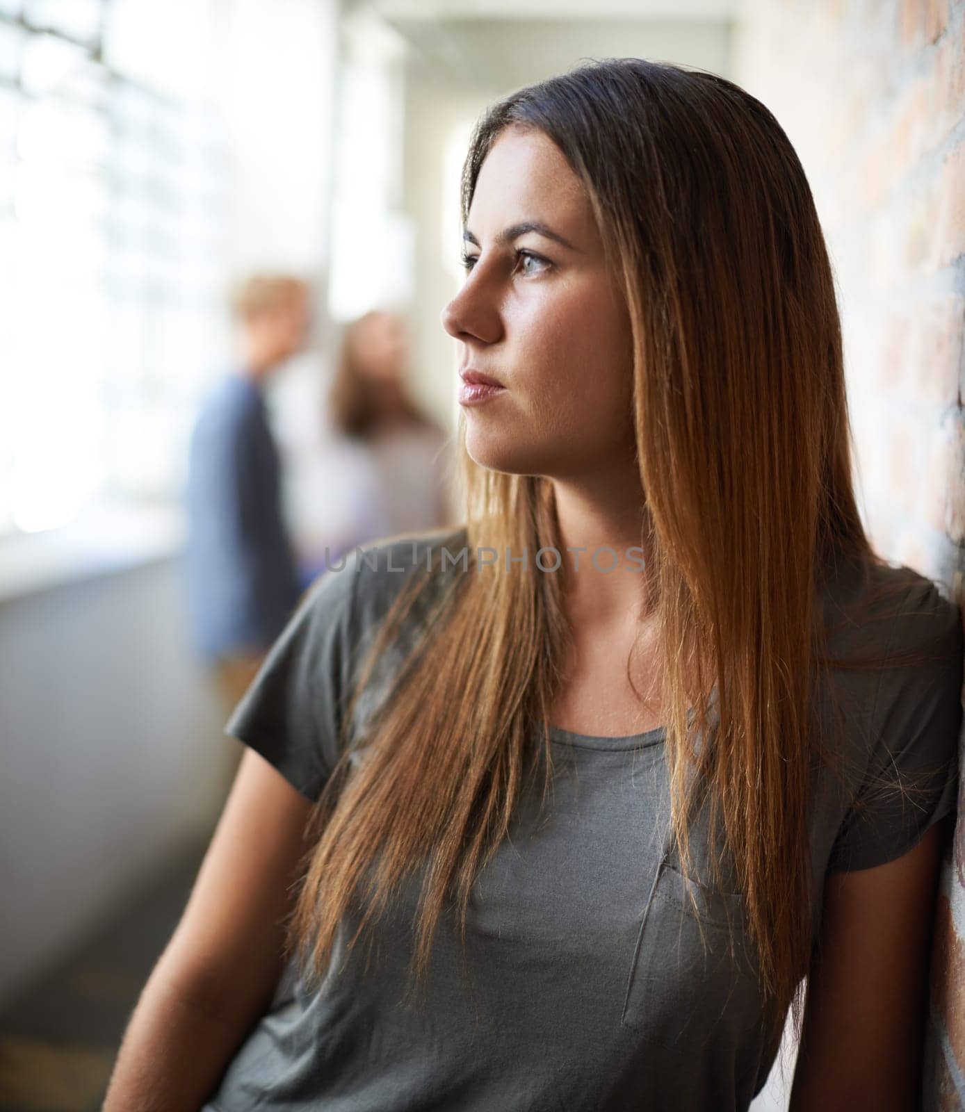 Deep in thought after class. an attractive young woman with people in the background