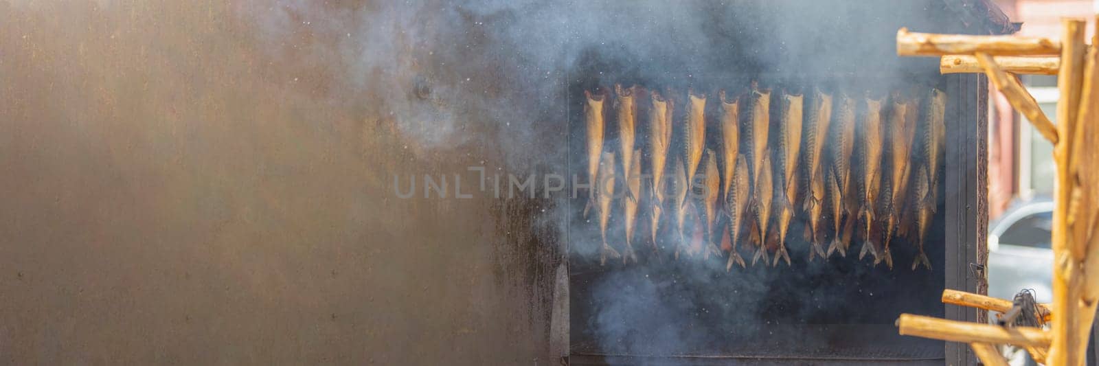 Advertising banner with the process of processing fish by smoking. Various types of fish in the process of smoking are hanging in a smokehouse with a place with copy space. by SERSOL