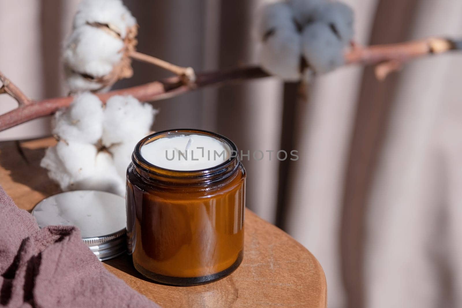 Soy wax hand made candle on wooden table and cotton branch, mockup design , shadow overlay. Mockup soy wax candle in natural style.