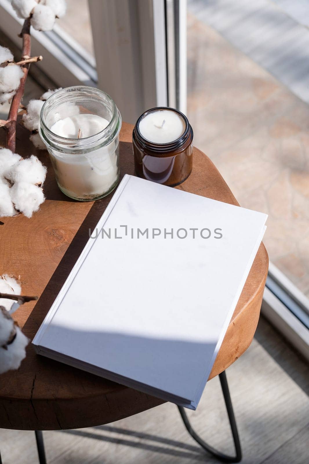 Magazine and book mockup design. Blank magazine on modern wooden table with candles , shadow overlay. Mockup soy wax candle in natural style.