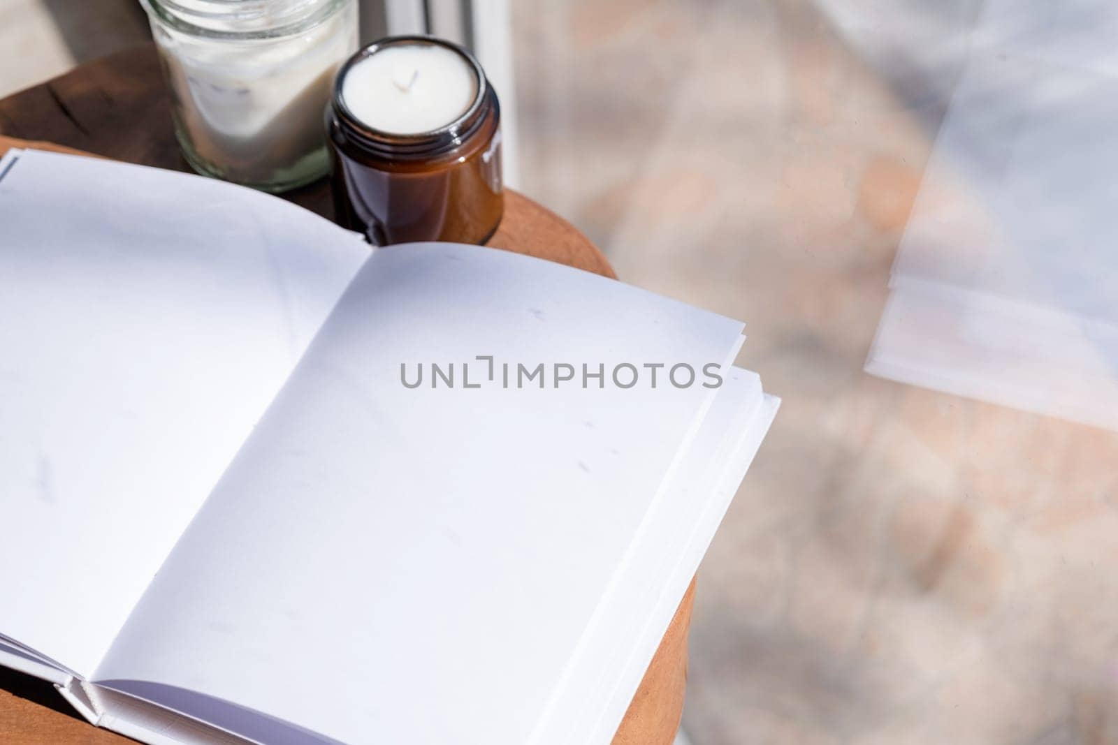 Magazine and book mockup design. Blank magazine on modern wooden table with candles , shadow overlay. Mockup soy wax candle in natural style.