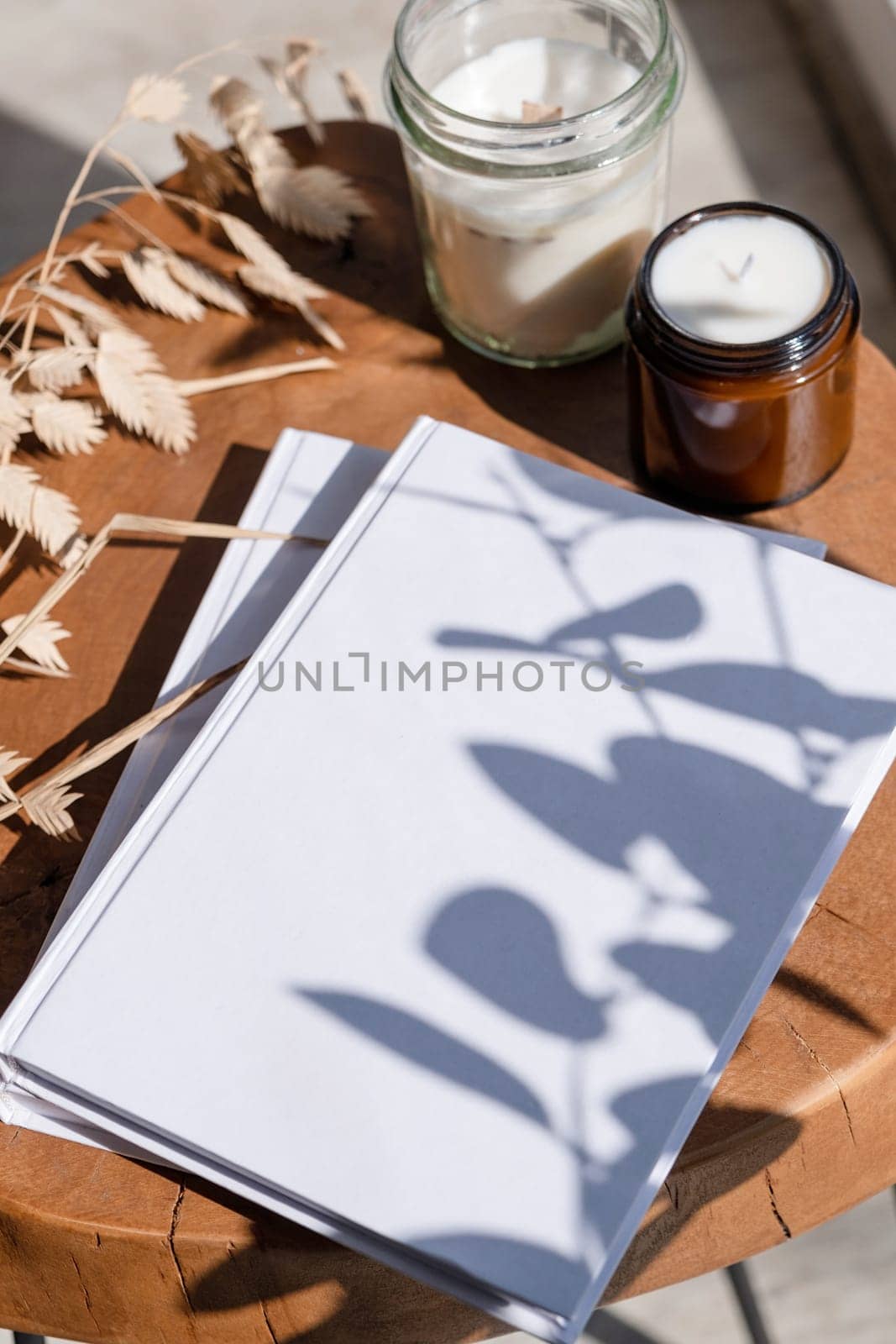 Magazine and book mockup design. Blank magazine on modern wooden table with candles , shadow overlay. Mockup soy wax candle in natural style.