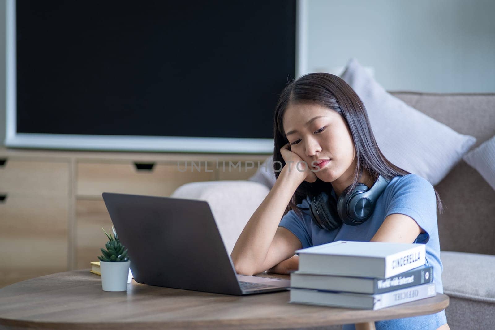 Bored young Asian woman sit at home, employee officer businesswoman working from home bored alone with laptop, high by wuttichaicci