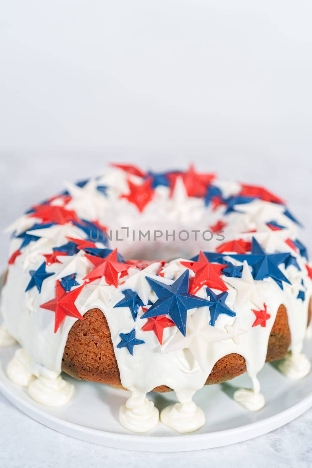 July 4th bundt cake covered with a vanilla glaze and decorated with chocolate stars on a white plate.