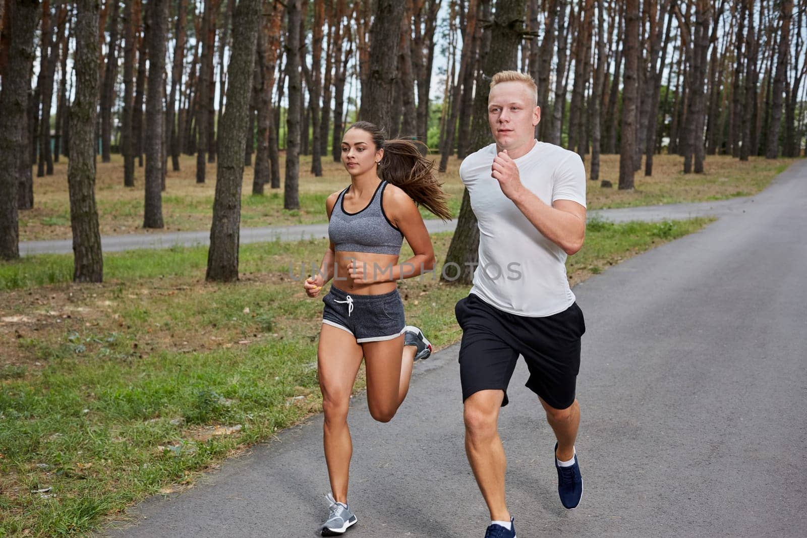 Couple running in forest. athletes make training, motion blur