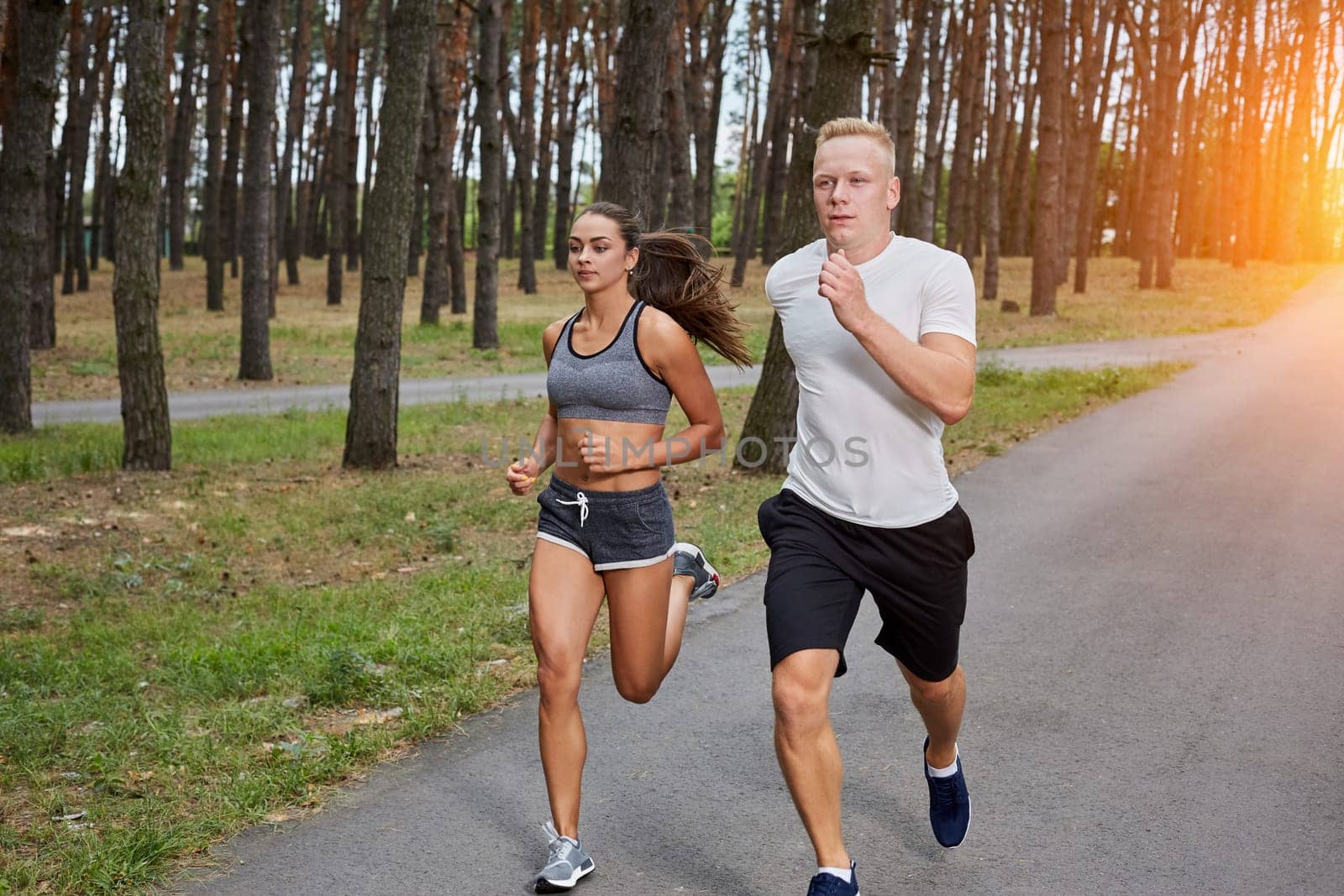 Couple running in forest. athletes make training, motion blur. with a sun flare