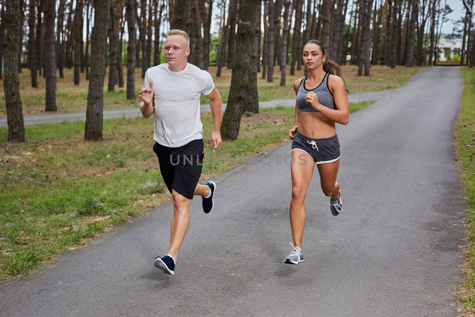 Couple running in forest. athletes make training, motion blur