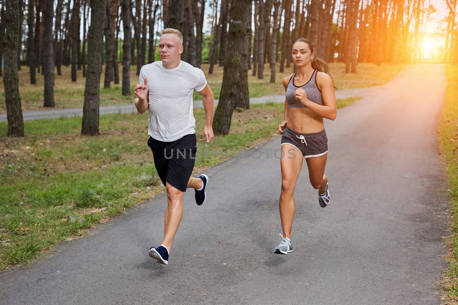 Couple running in forest. athletes make training, motion blur. with a sun flare