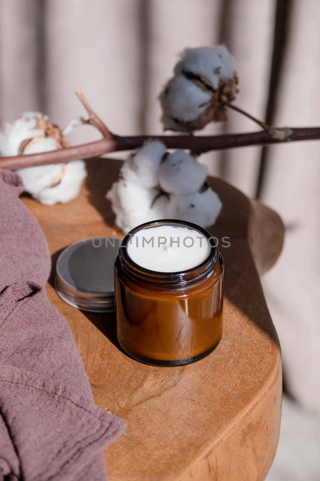 Soy wax hand made candle on wooden table and cotton branch, mockup design , shadow overlay. Mockup soy wax candle in natural style.