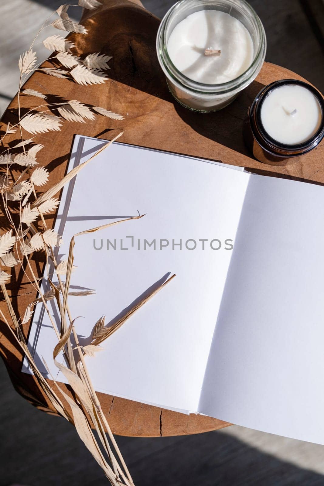 Magazine and book mockup design. Blank magazine on modern wooden table with candles , shadow overlay. Mockup soy wax candle in natural style.