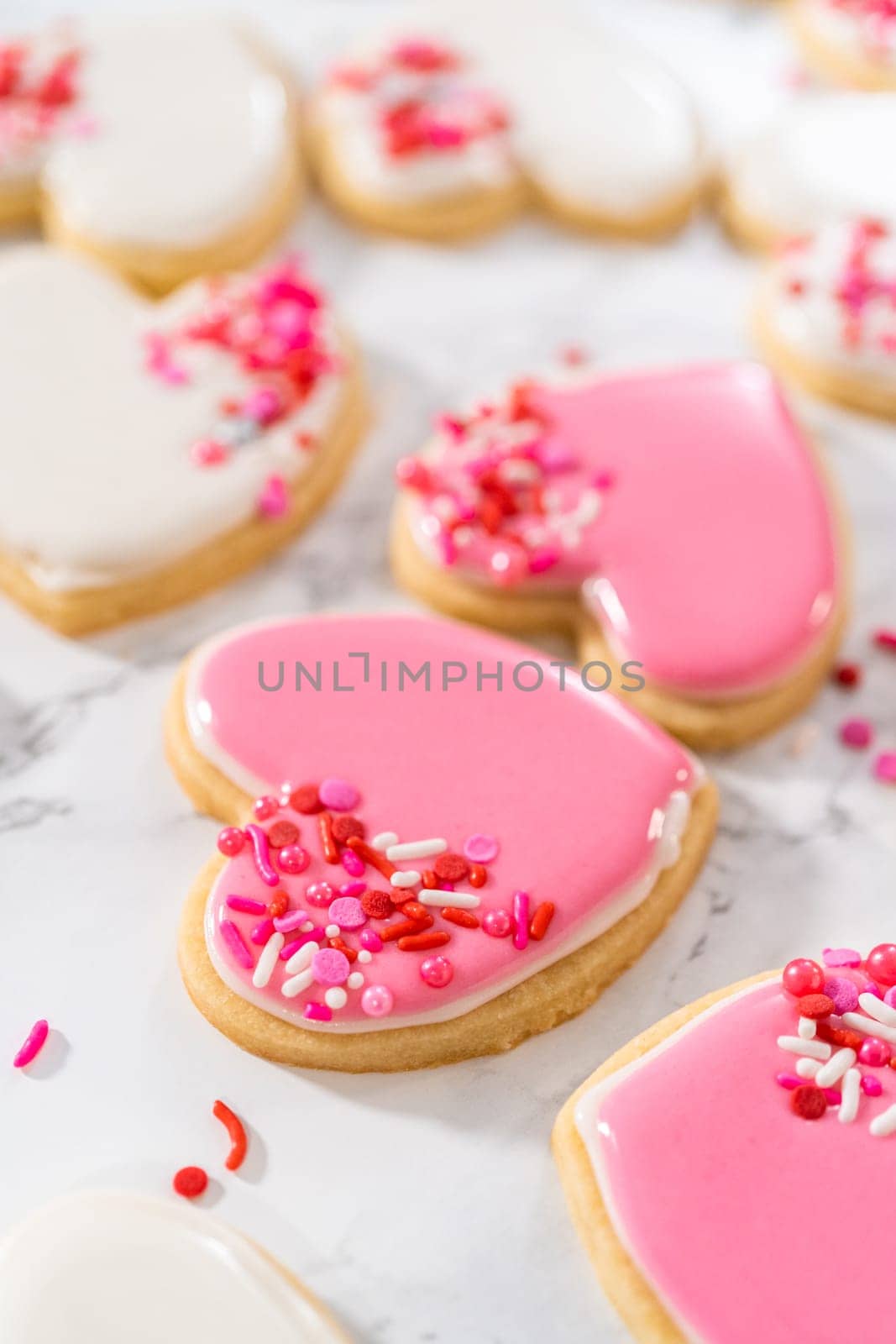 Decorating heart-shaped sugar cookies with pink and white royal icing for Valentine's Day.