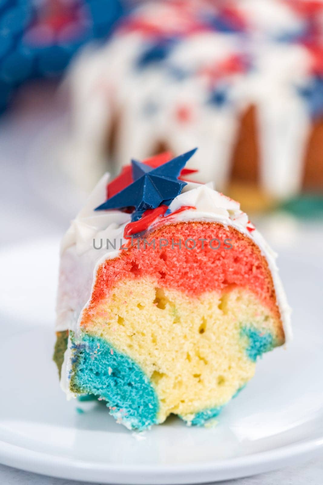 Slice of July 4th bundt cake covered with a vanilla glaze and decorated with chocolate stars.