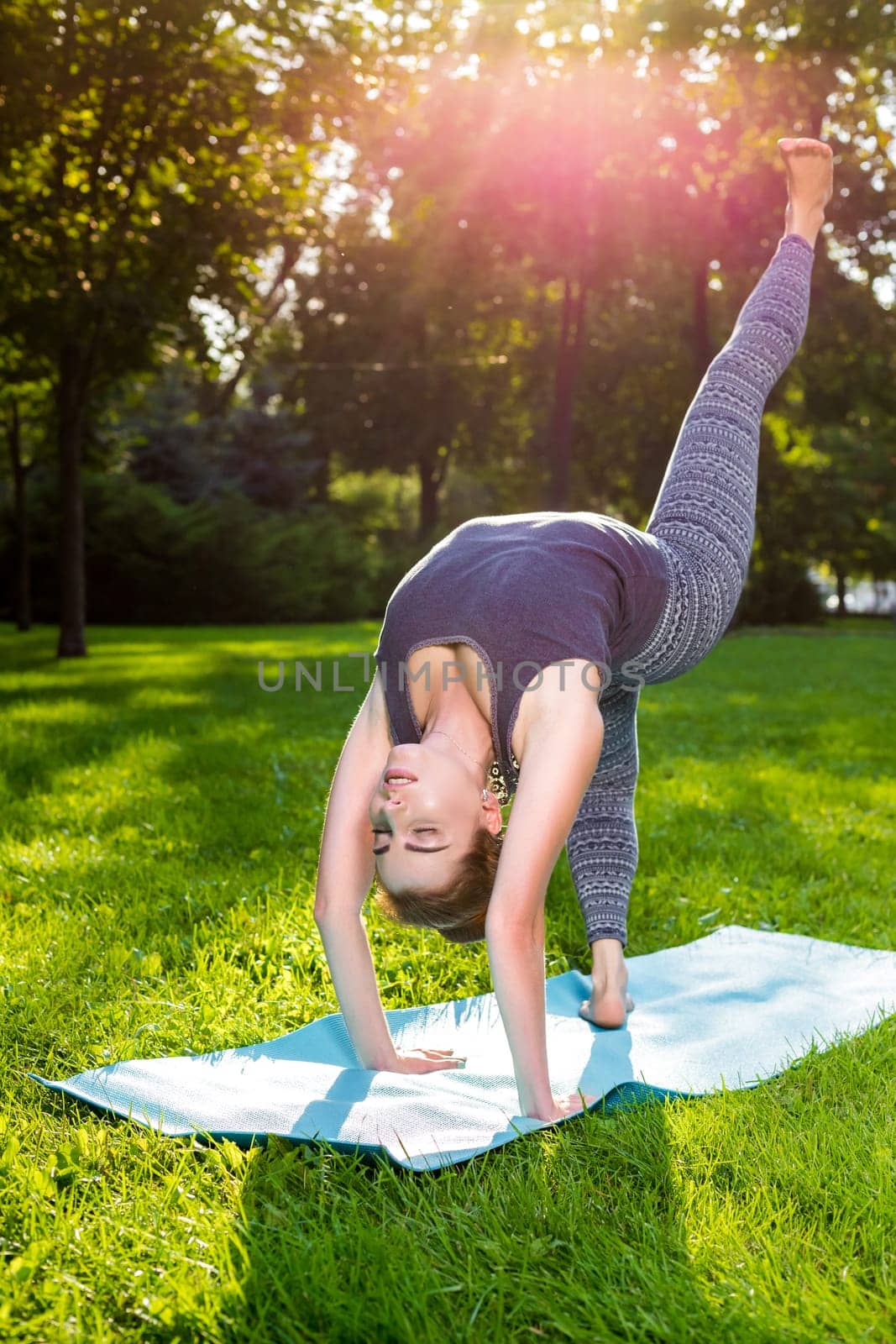 Young fitness woman meditation in a city park.Yoga at sunset in the park. Girl is practicing yoga. Fitness training outdoors. Attractive fitness woman. Workout outdoors. Healthy lifestyle. sun flare