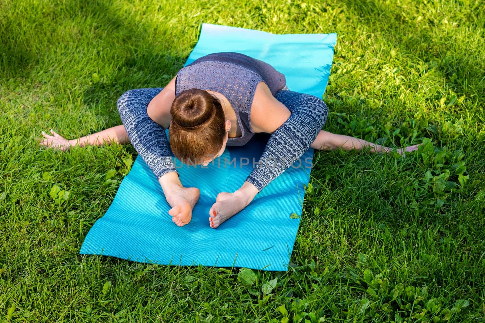 Young woman doing yoga exercises in the summer city park. by nazarovsergey