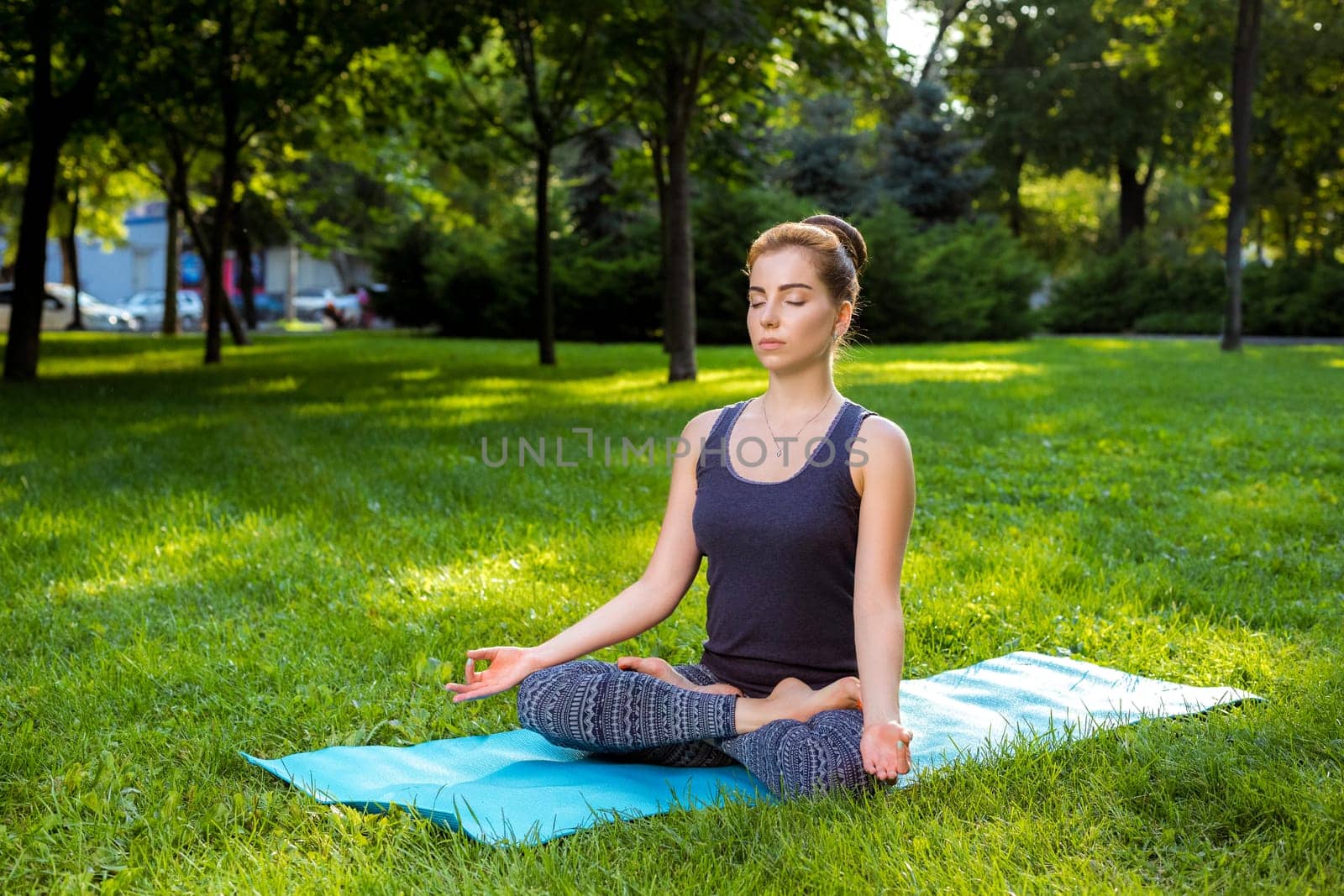 Young woman doing yoga exercises in the summer city park. by nazarovsergey