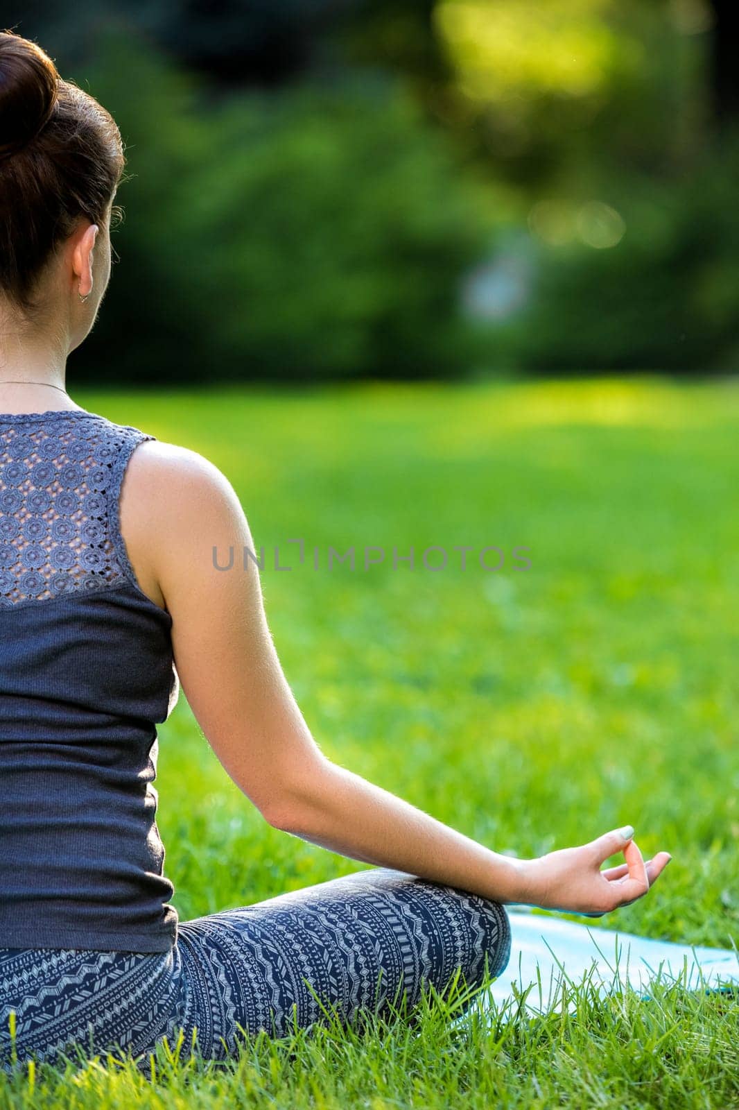 Meditating woman in meditation in city park in yoga pose. Girl relaxing with serene relaxed expression outside in summer. Beautiful young Caucasian female model. Close up