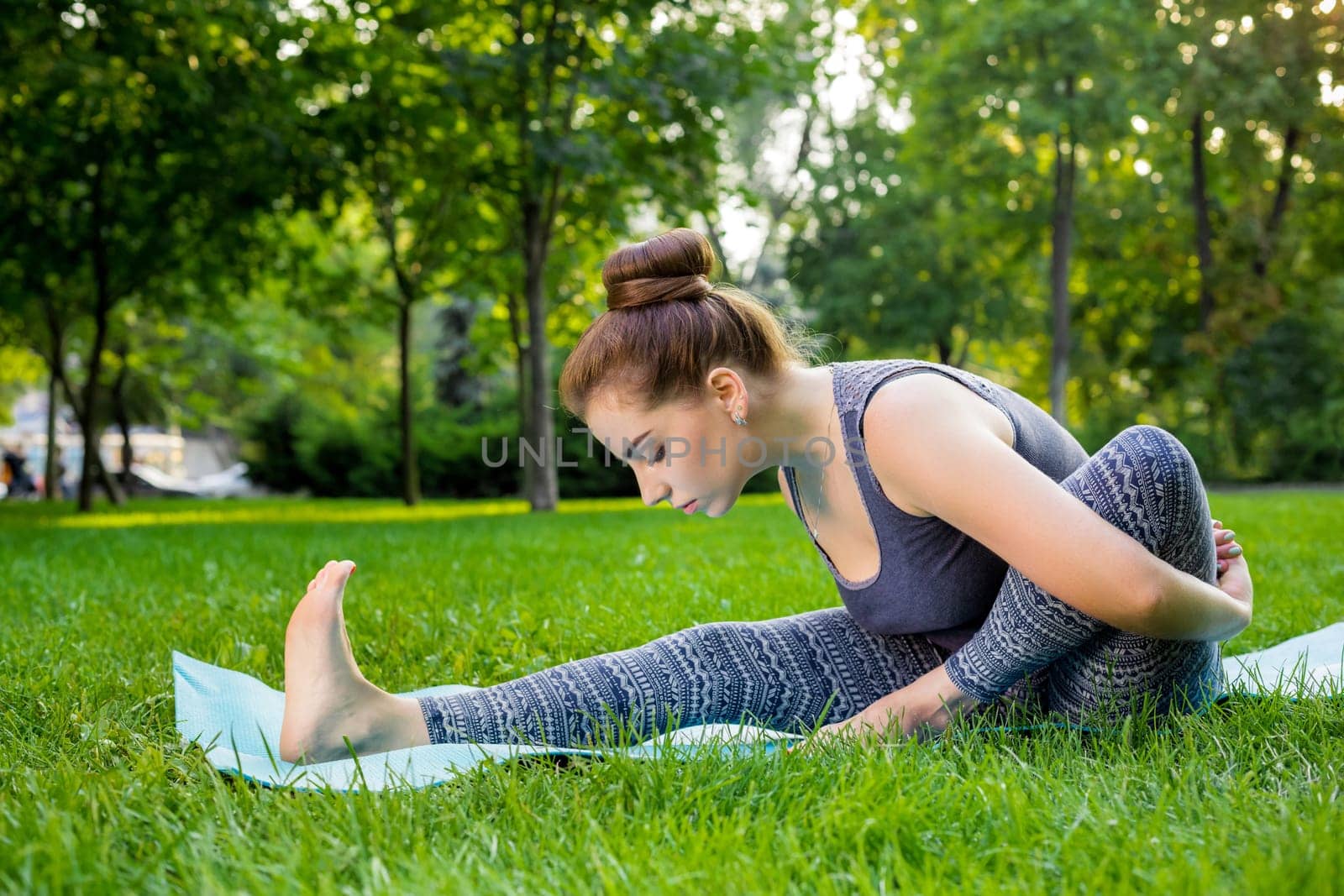 Young fitness woman meditation in a city park.Yoga at sunset in the park. Girl is practicing yoga. Fitness training outdoors. Attractive fitness woman. Workout outdoors. Healthy lifestyle