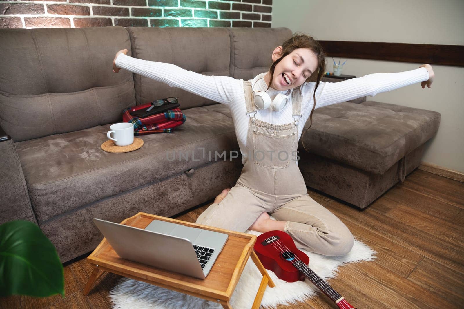 Overjoyed happy young woman raising her hands feeling excited, funny independent girl rejoices having fun enjoying freedom and learning.