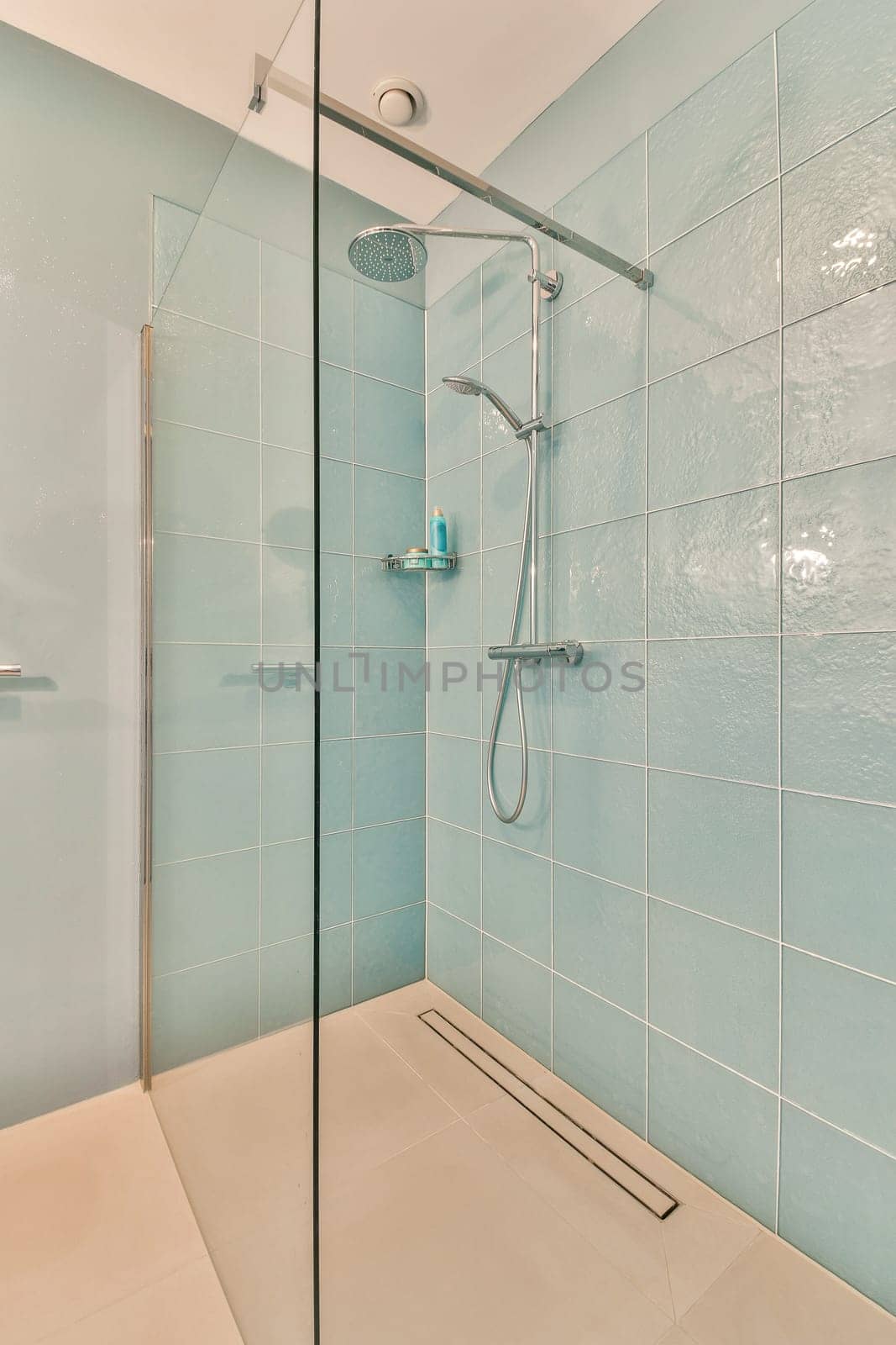 a bathroom with blue tiles on the wall and shower head mounted to the wall in front of the glass door