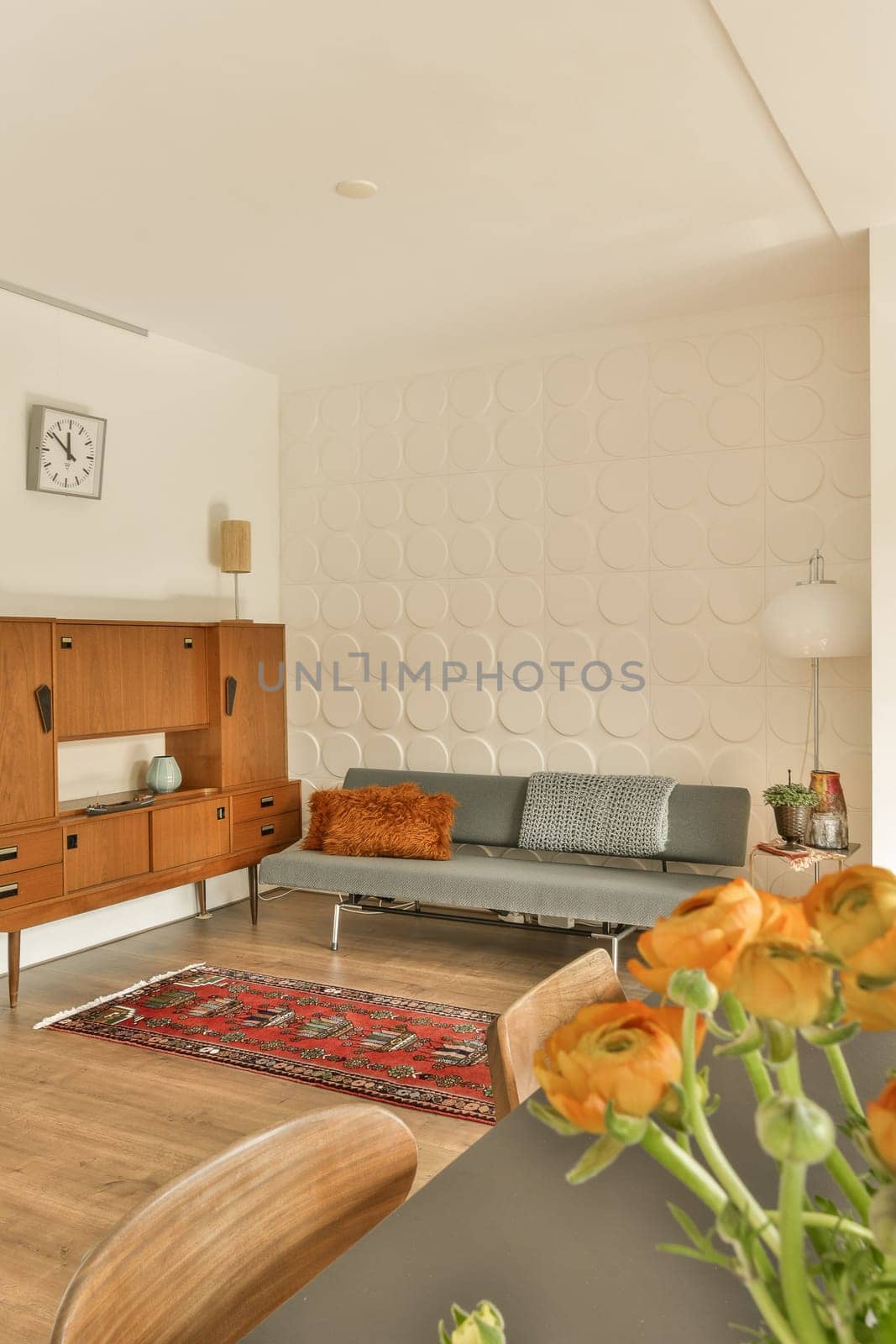 a living room with wood furniture and flowers in the vase on the table next to the couch is an orange flower
