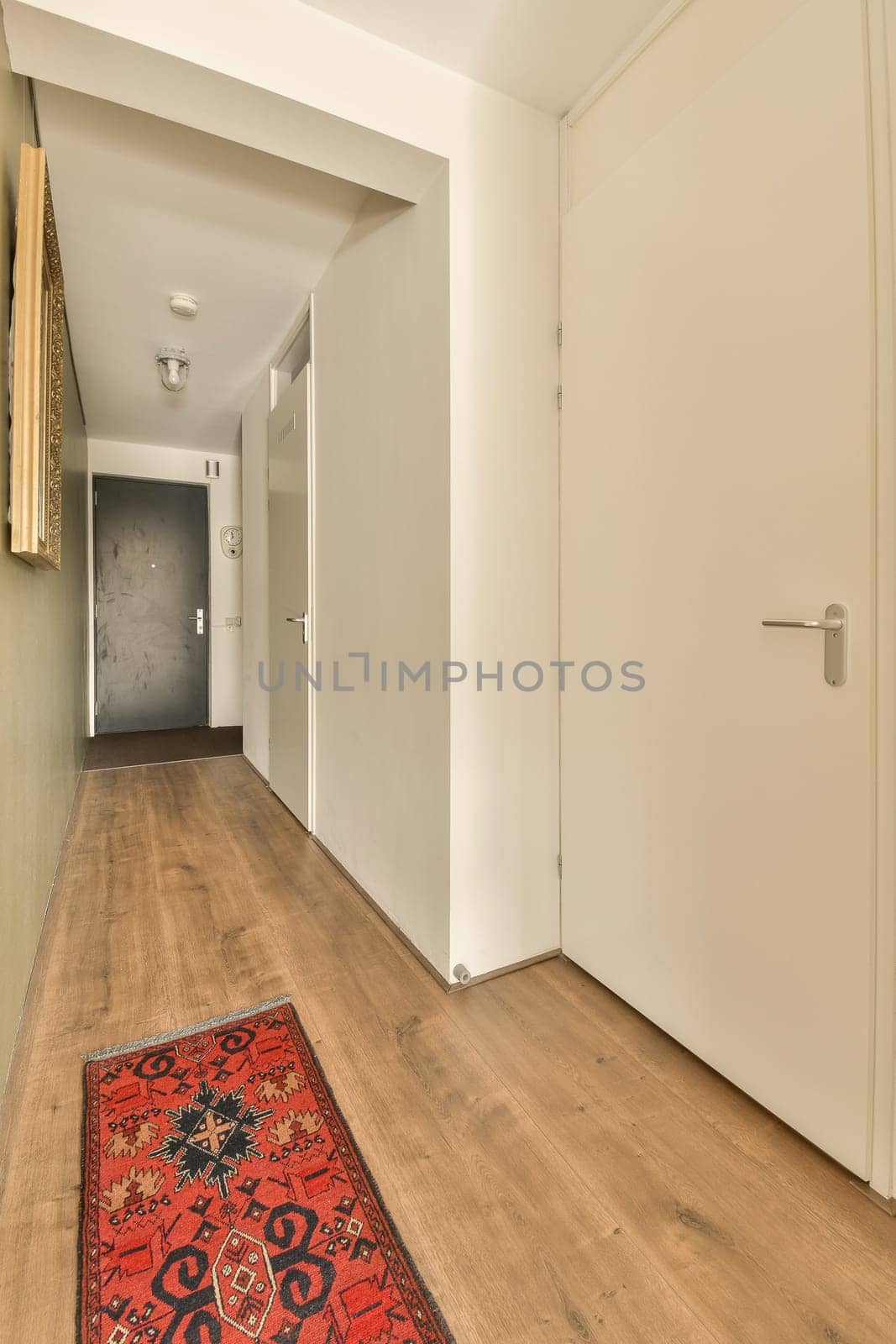 a hallway with white walls and a red rug on by casamedia