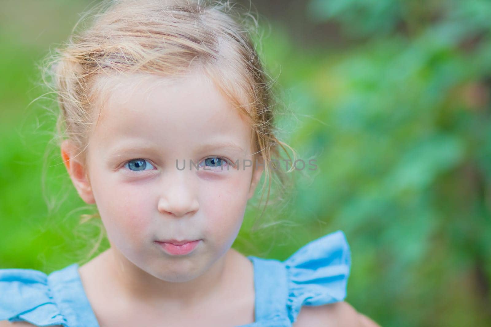 Sweet little girl, two years old. The girl smiles, looks into the camera. Blue eyes, blonde hair.