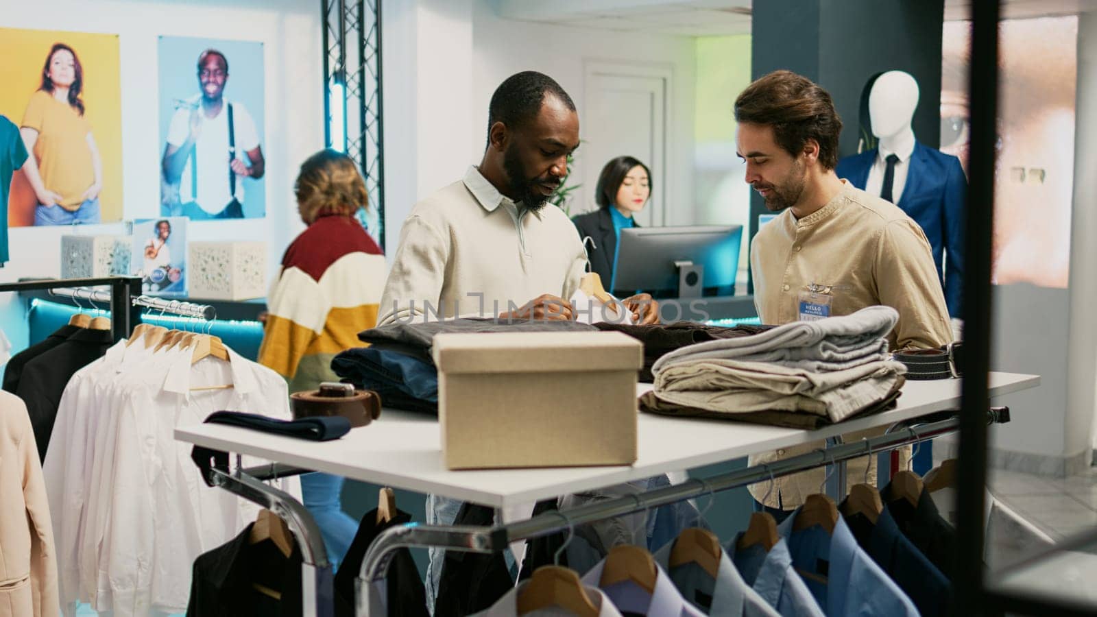 Customer and assistant looking at formal wear in boutique, retail store employee helping shopper to buy new clothes collection. Male client trying to improve wardrobe, fashion style.