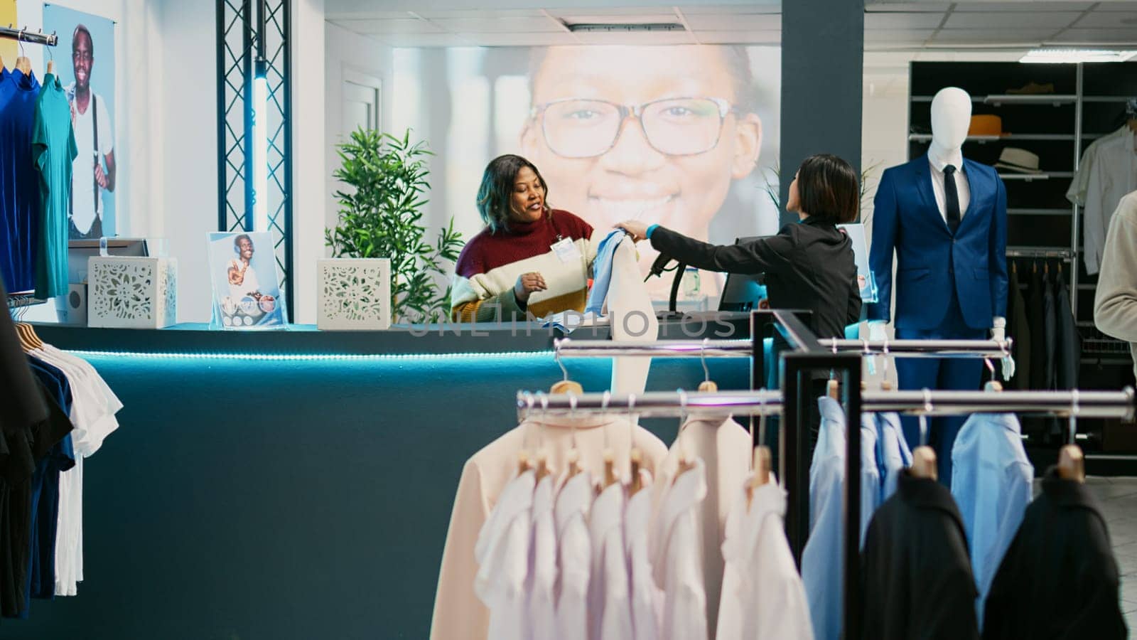 Female customer buying trendy clothes in retail store, making purchase at pos terminal. Asian shopaholic person paying for merchandise at fashion boutique, commercial activity.