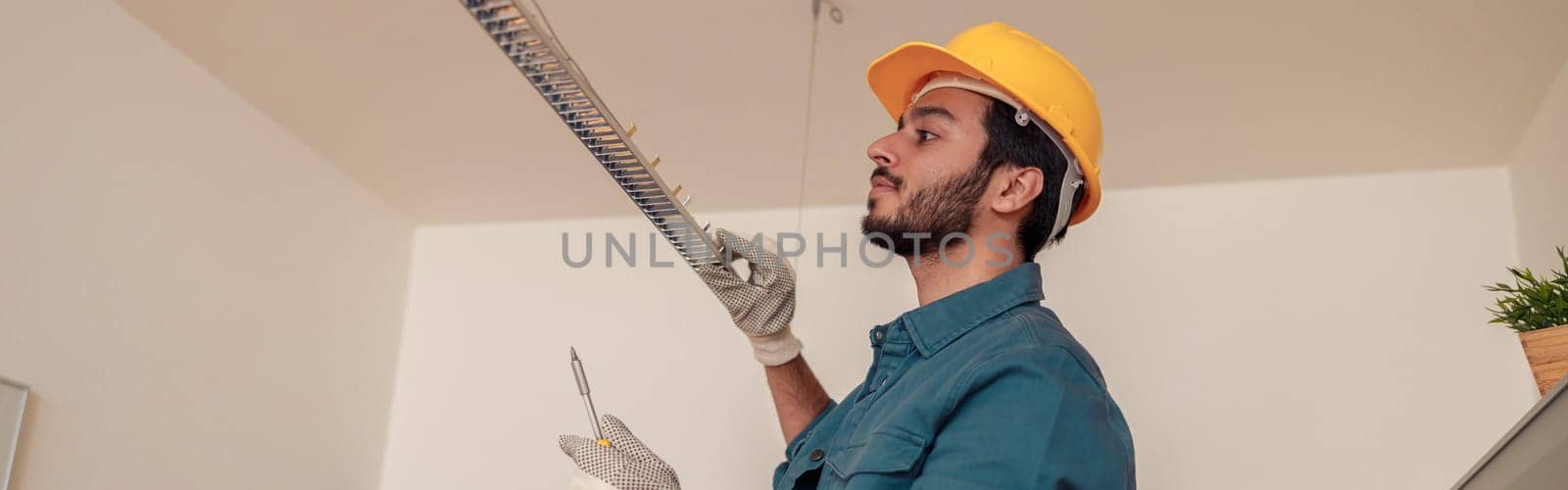 Electrician worker is installing electric lamps light in kitchen. Construction decoration concept