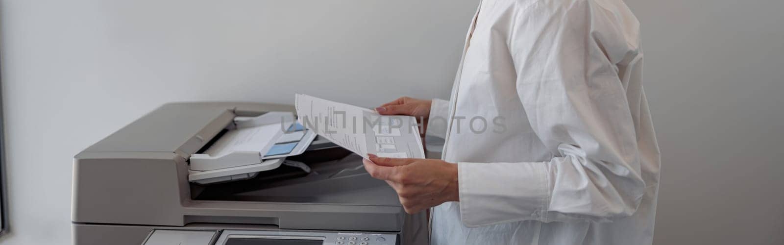 Focused woman worker scanning document on photocopy machine In modern office. Blurred background
