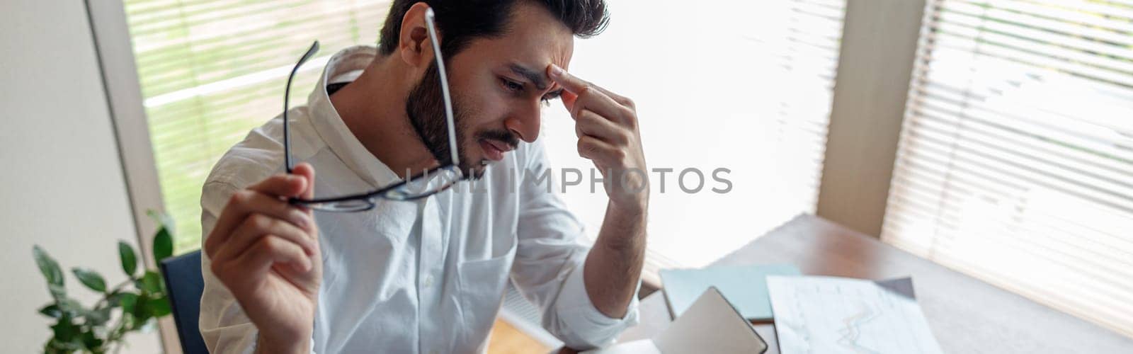 Tired indian businessman in suit working with documents from home office by Yaroslav_astakhov