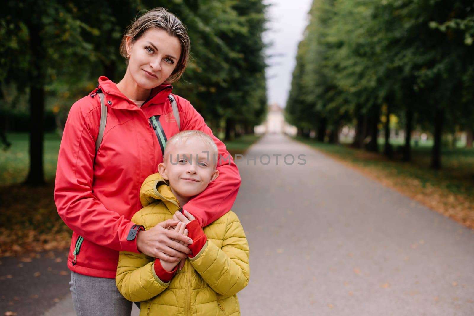 mother and son stand hugging in the park in the fall. happy mother playing with her son in the park. Mother hugs her son while standing in the forest in autumn.