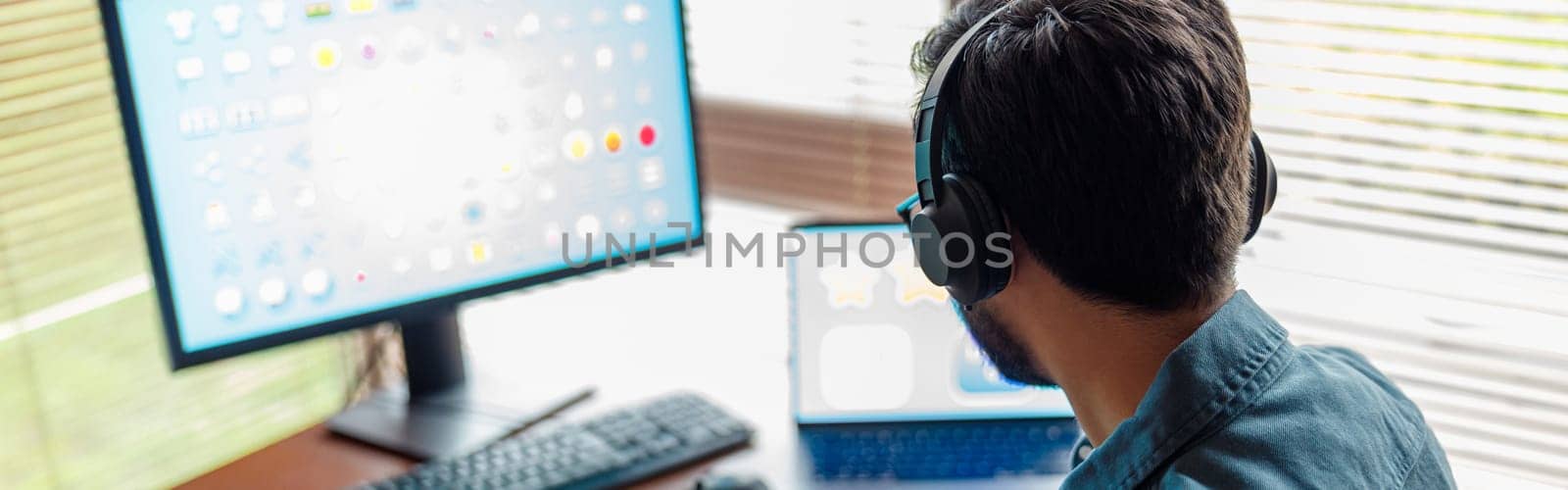 Back view of man designer in headphones works in home office. High quality photo