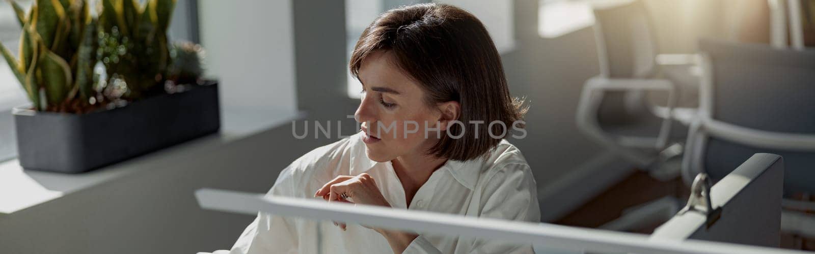 Focused european business woman working laptop and making notes while sitting in modern office by Yaroslav_astakhov