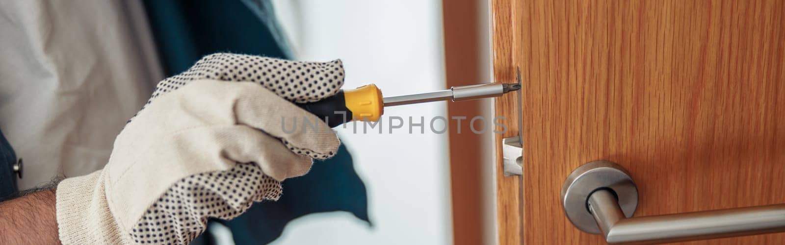 Locksmith workman in uniform installing door knob. Professional repair service. Maintenance Concept