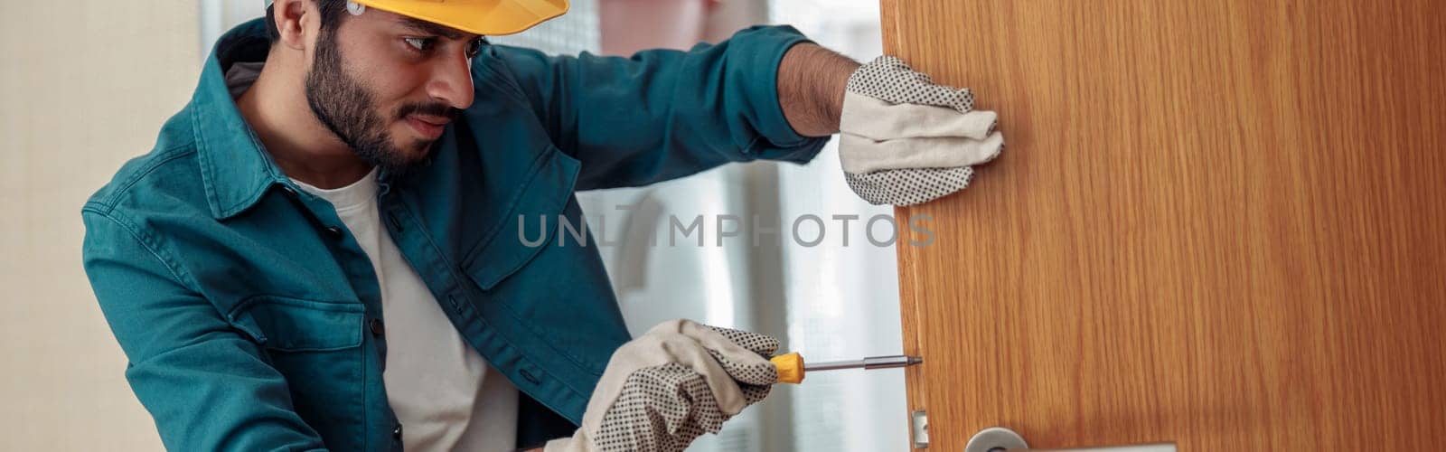 Locksmith workman in uniform installing door knob. Professional repair service by Yaroslav_astakhov