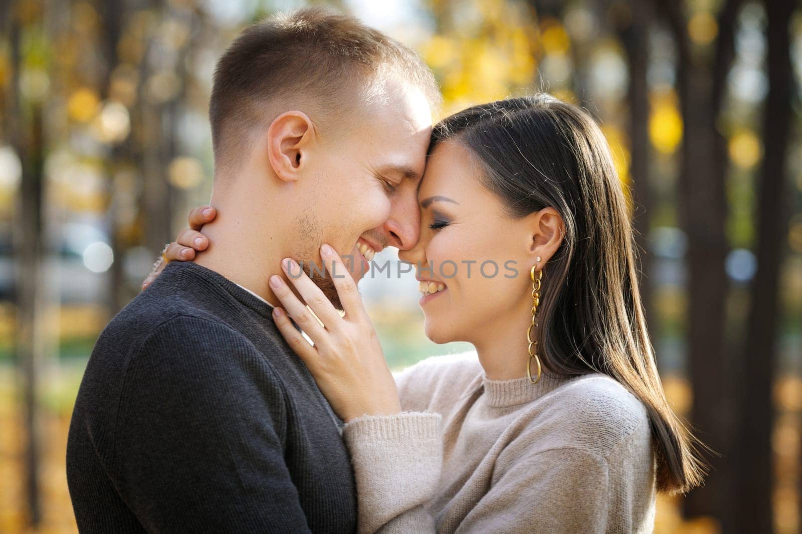 Portrait of young interracial couple in love in autumn park.