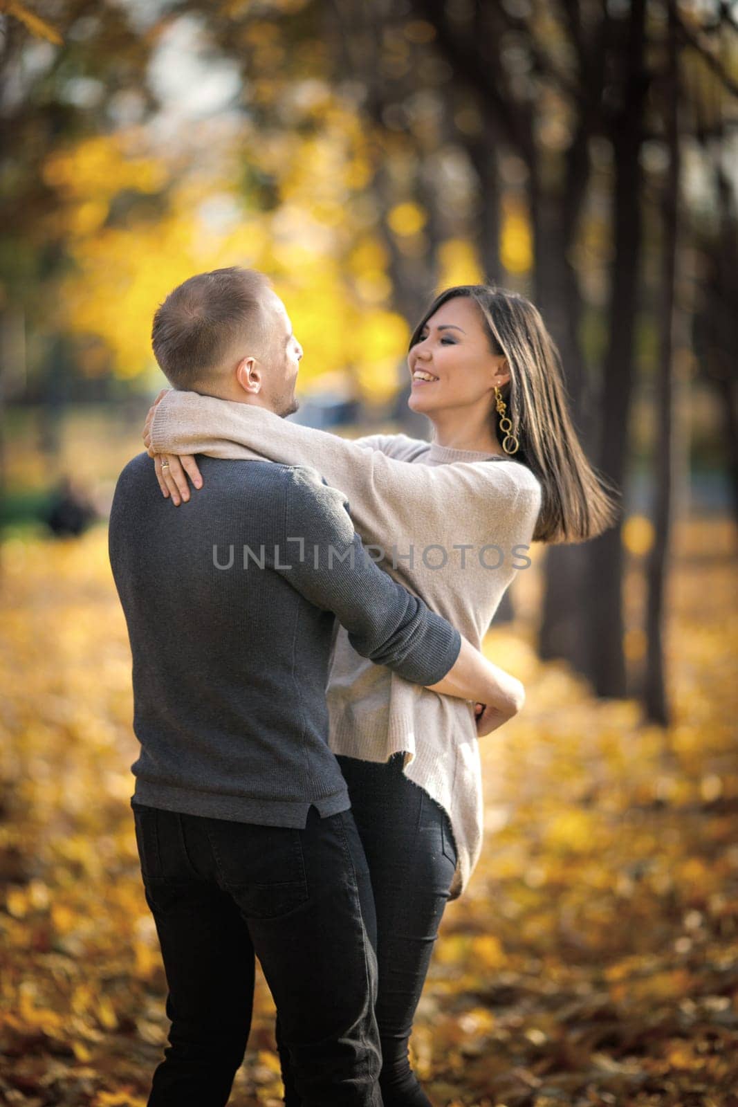 Couple of happy lovers dancing in autumn park on a date. Vertical, copy space