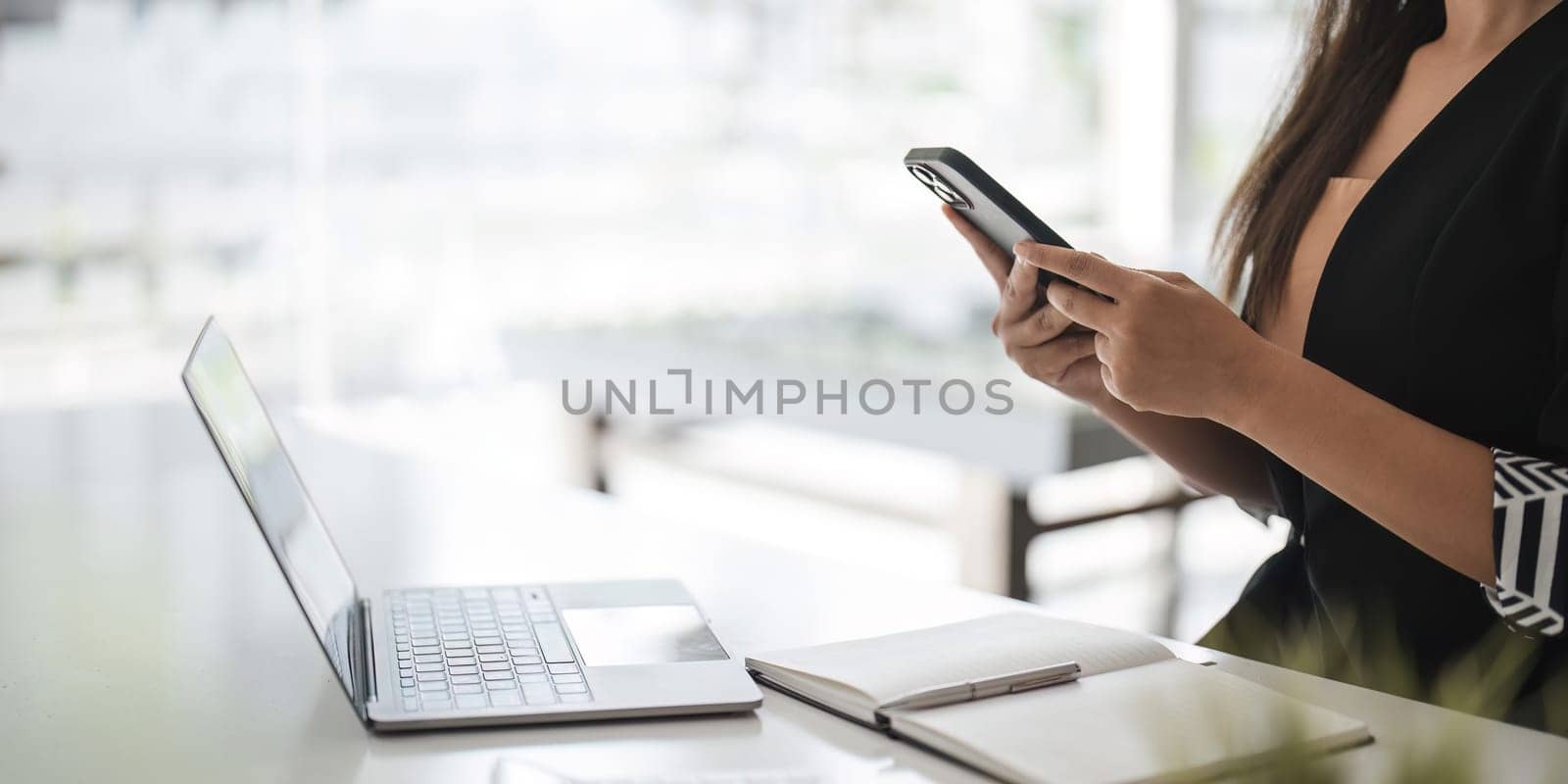 Asian businesswoman in formal suit in office happy and cheerful during using smartphone and working..