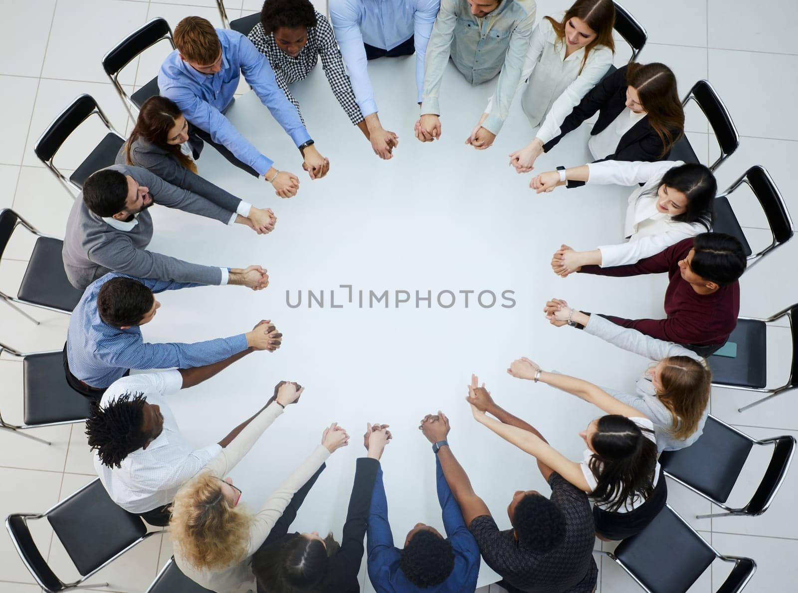 a large group of people sitting at a round table with their arms outstretched by Prosto