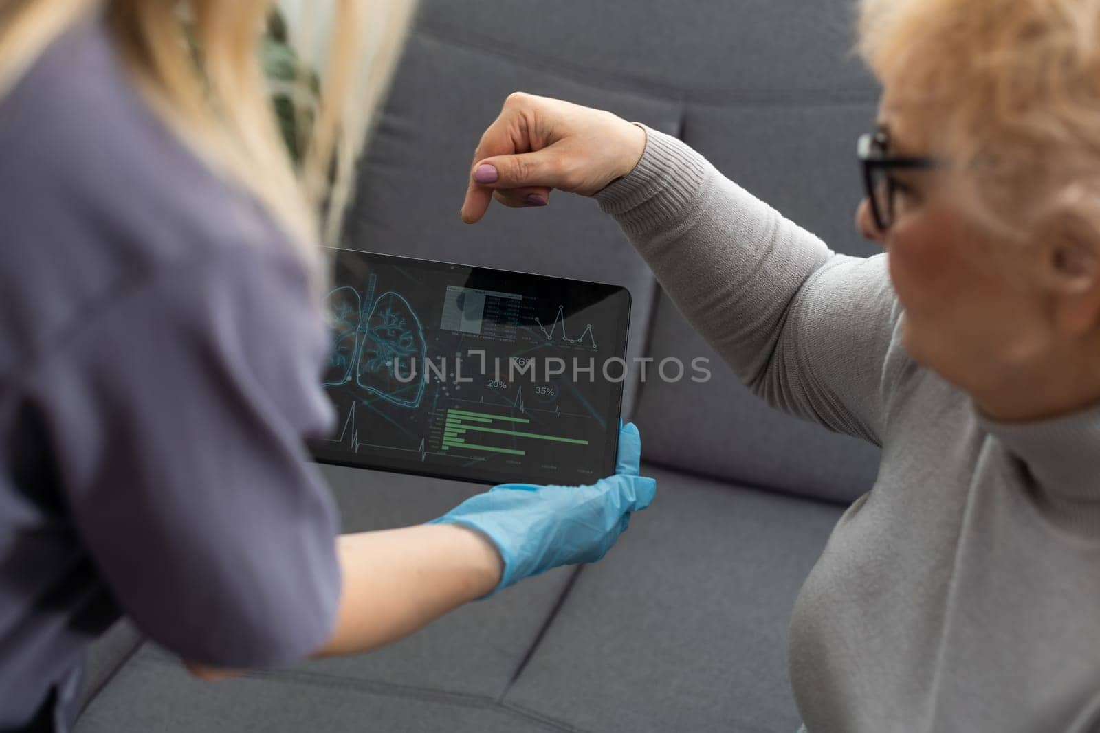 Doctor or nurse caregiver holding a tablet computer with senior woman at home or nursing home by Andelov13